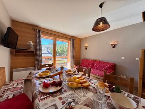 Un coin repas avec une table mise pour le petit-déjeuner, un canapé et un téléviseur fixé au mur.