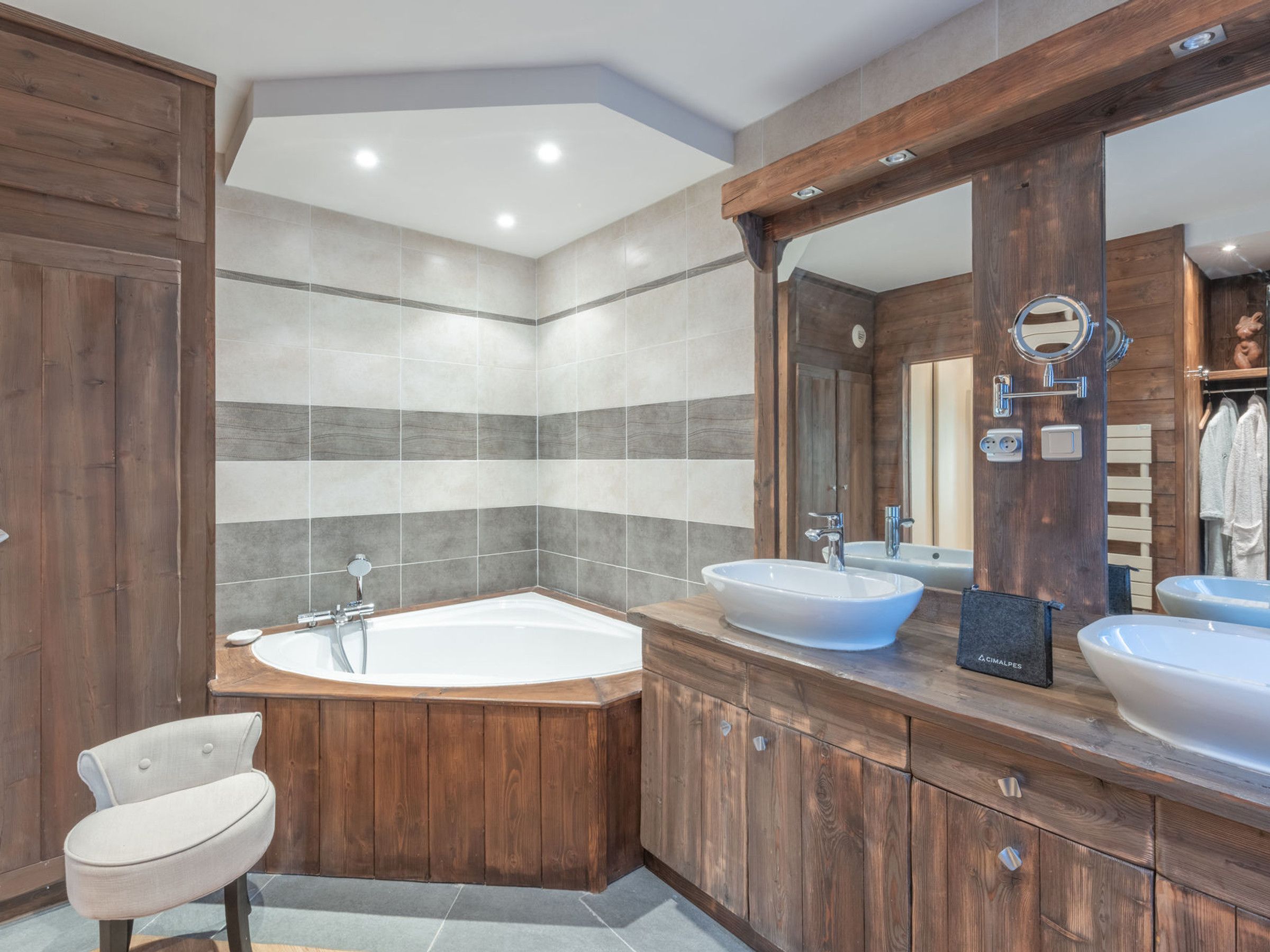 Een moderne badkamer met een vrijstaand bad, twee wastafels en een grote spiegel.