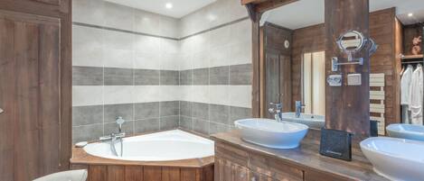 Een moderne badkamer met een vrijstaand bad, twee wastafels en een grote spiegel.