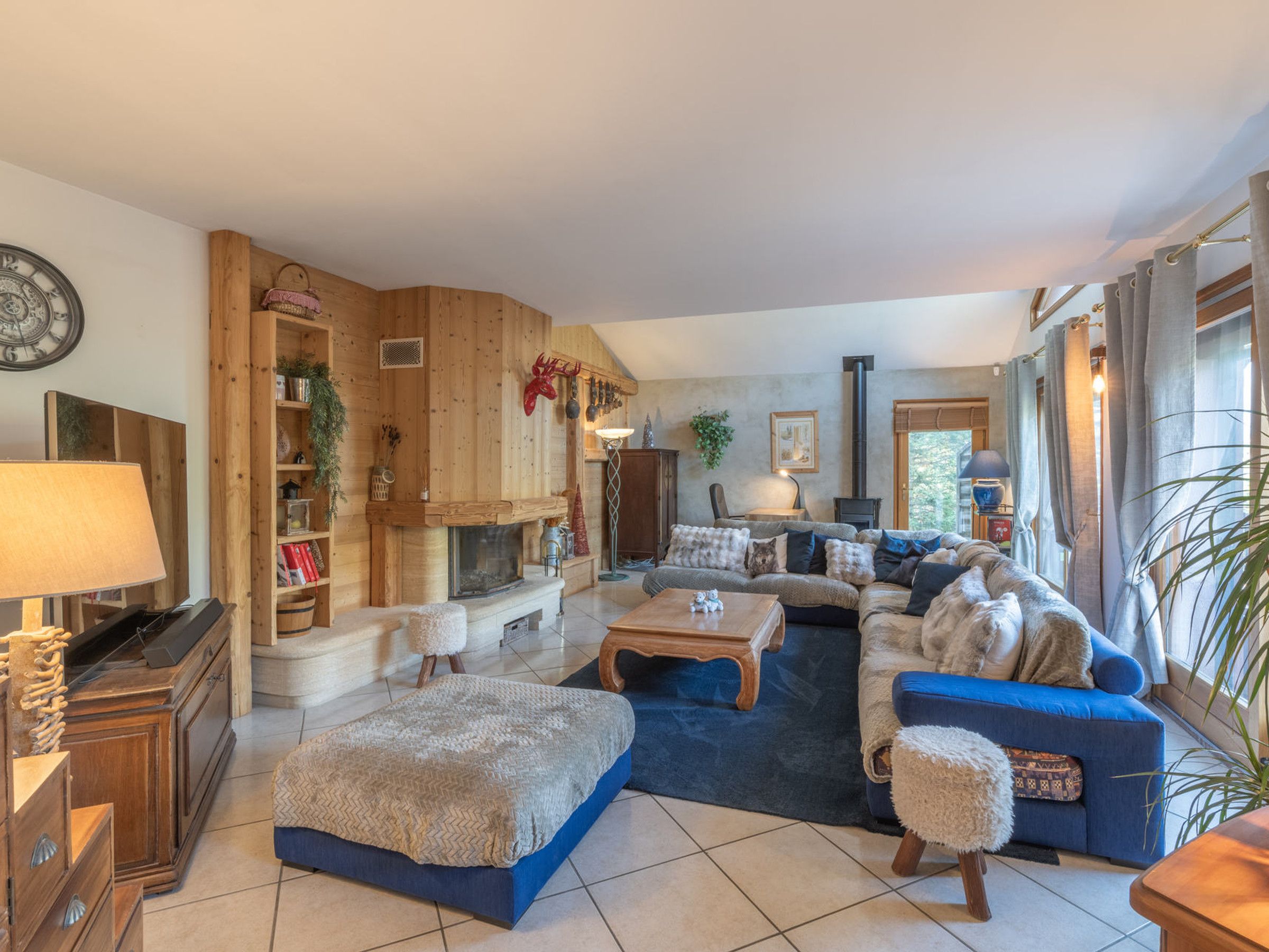 Uma sala de estar aconchegante com lareira, um sofá azul e uma estante de madeira.