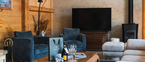 A cozy living room with a wooden wall, a flat-screen TV, and a fireplace.