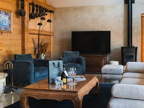 Ein gemütliches Wohnzimmer mit einer Holzwand, einem Flachbildfernseher und einem Kamin.