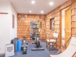 Ein Fitnessraum mit Trainingsgeräten, einer blauen Matte, einem weißen Luftreiniger und einer Holzwand.