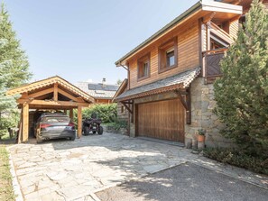 Eine Holzhütte mit einem gepflasterten Zugang, einer überdachten Garage und einer zusätzlichen Garage.