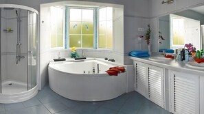 Ein modernes Badezimmer mit einer freistehenden Badewanne, einer in Glas abgeschlossenen Dusche und einem großen Fenster mit Aussicht.