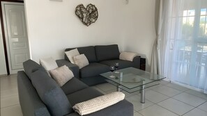 Ein modernes Wohnzimmer mit einem Ecksofa, einem Glastisch und einer Wanddekoration.
