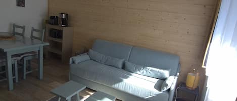 A living room with a sofa, a coffee table, and a dining table with chairs.