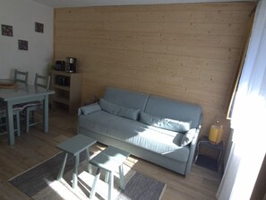 A living room with a sofa, a coffee table, and a dining table with chairs. - Charming apartment - 5 guests (Les Carroz d'Arâches)