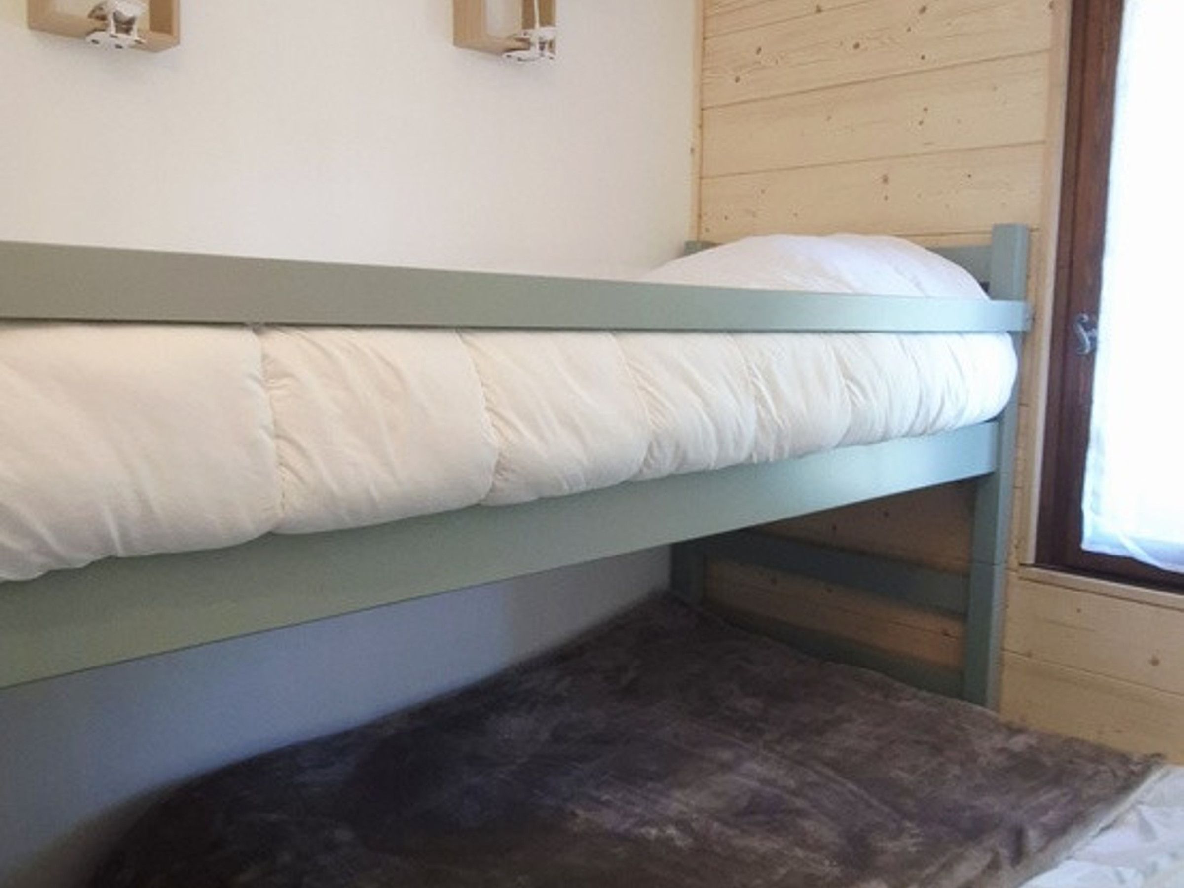 Ein Etagenbett mit einem Kissen und einem dunkel gefärbten Kissen auf der Unterliege.