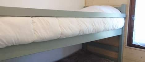 A bunk bed with a pillow and a dark-colored pillow on the lower bunk.