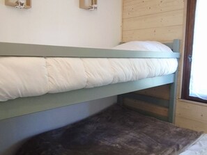 Ein Etagenbett mit einem Kissen und einem dunkel gefärbten Kissen auf der Unterliege.