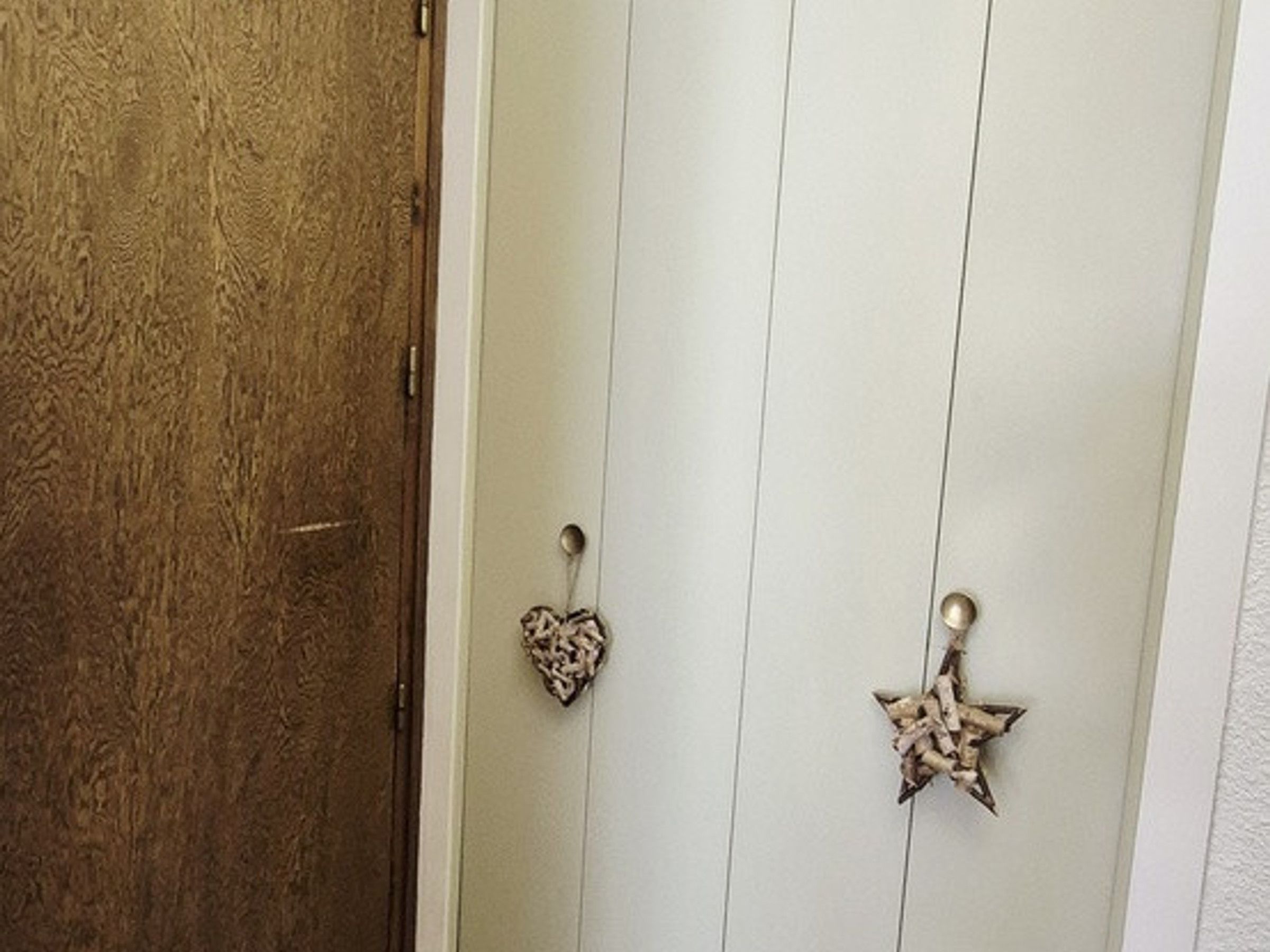 A door with a textured wooden panel and two decorative metal handles, one shaped like a heart and the other like a star.