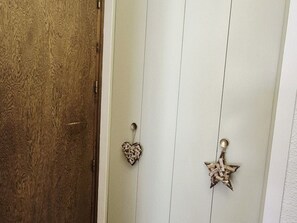 A door with a textured wooden panel and two decorative metal handles, one shaped like a heart and the other like a star. - Charming apartment - 5 guests (Les Carroz d'Arâches)