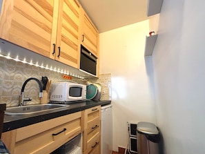 A compact kitchen with wooden cabinets, a microwave, a toaster, and a sink. - Cozy studio, pets welcome - 2 guests (Samoëns)