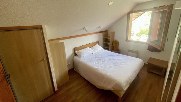 A bedroom with a single bed, a wooden wardrobe, a small bedside table, a nightstand, and a window with a view of greenery. - Convenient apartment, pets allowed - 6 guests (Valloire)
