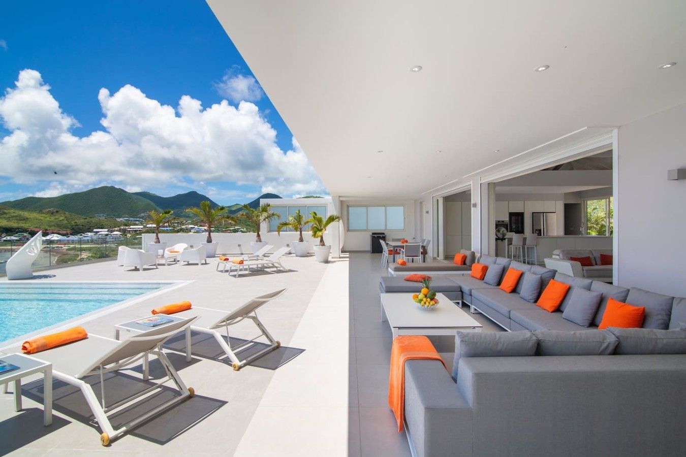 A modern living area with a pool, outdoor seating, and a view of the mountains.