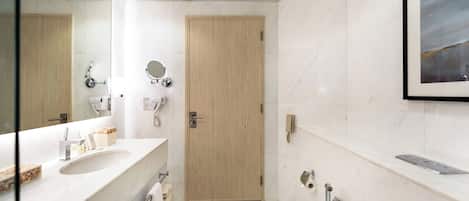 A modern bathroom with a large mirror, two sinks, a shower, and a toilet.