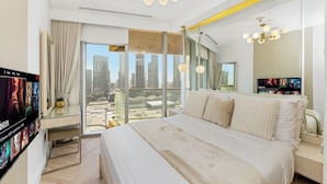 Habitación de hotel moderna con una cama grande, vistas a la ciudad y un televisor mostrando una película.