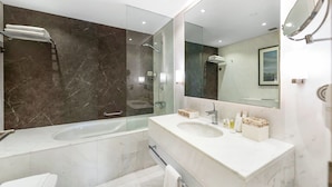 Un baño moderno con ducha envuelta en vidrio, tocador doble y un espejo grande.