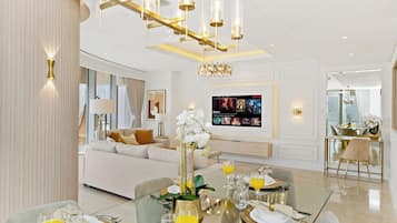 Ein modernes Wohnzimmer mit einer Couch, einem Esstisch für vier Personen und einem an der Wand befestigten Fernseher.