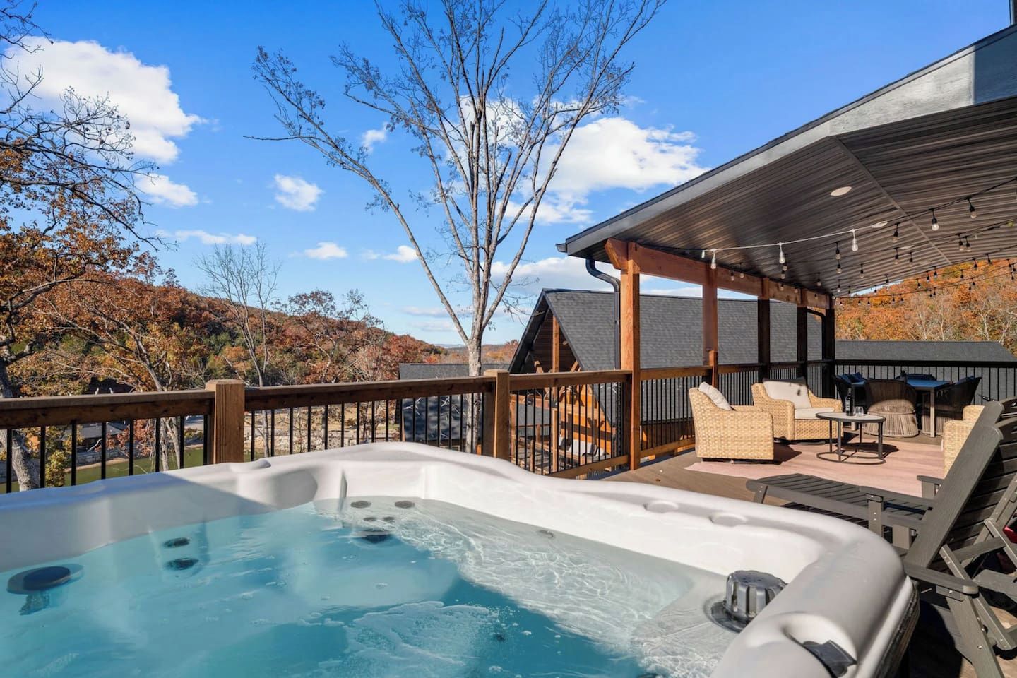 Een hottub op een terras met zitplaatsen buiten en uitzicht op een berg.