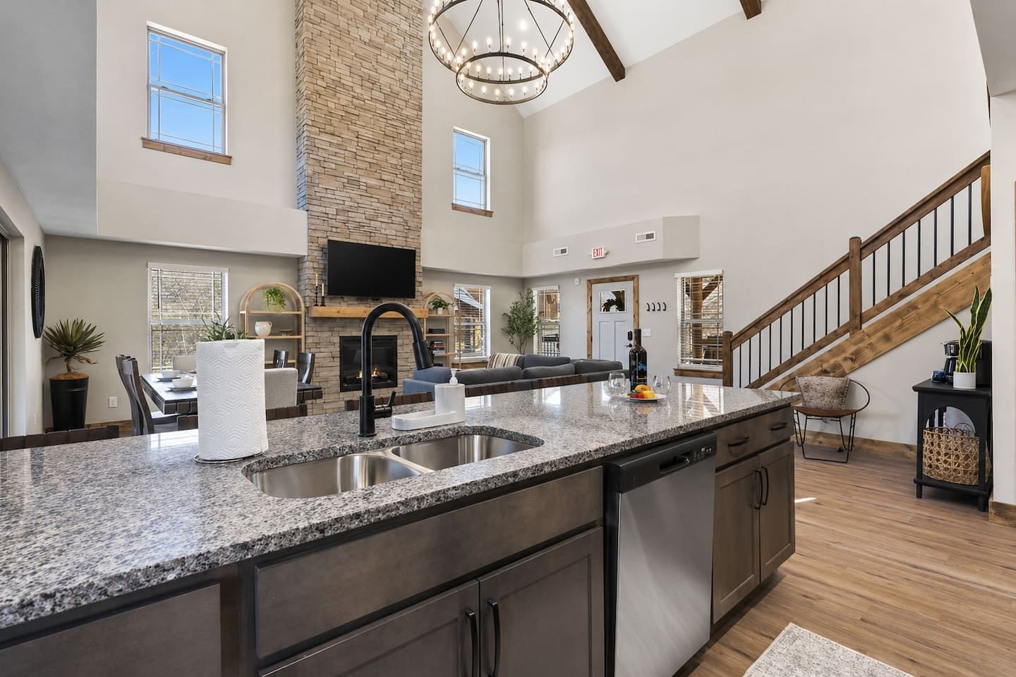 A spacious kitchen with a large island, a fireplace, and a staircase leading to an upper level.