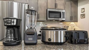 Une cuisine équipée d’une machine à café, d’un mixeur, d’une mijoteuse, d’un four à micro-ondes et d’un grille-pain.