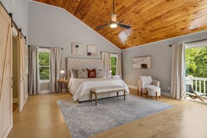 A bedroom with a large bed, a ceiling fan, and a view of the outdoors. - Woodland Dreams by Carolina Mornings | Hot Tub, Fire Pit, & Mtn Views Near AVL (Swannanoa)