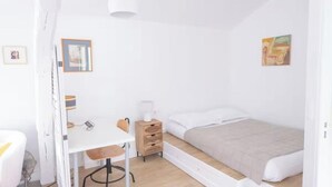 A bedroom with a bed, a desk, a chair, a bedside table, and a lamp. - A CLASSIC FRENCH CHARACTER WITH A FRESH, CONTEMPORARY INTERIOR. (Paris)