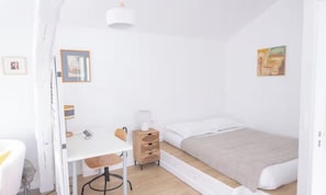 A bedroom with a bed, a desk, a chair, a bedside table, and a lamp. - SPACIOUS RENOVATED STUDIO IN THE HEART OF PARIS (Paris)