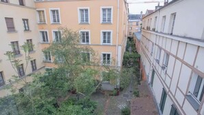 A courtyard with multiple buildings, trees, and a small garden area. - A CLASSIC FRENCH CHARACTER WITH A FRESH, CONTEMPORARY INTERIOR. (Paris)