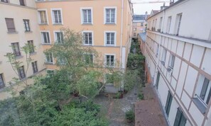A courtyard with multiple buildings, trees, and a small garden area. - SPACIOUS RENOVATED STUDIO IN THE HEART OF PARIS (Paris)
