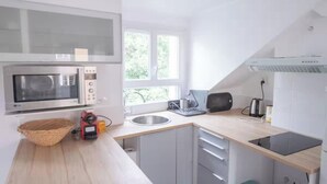 A modern kitchen with a microwave, toaster, and sink. - A CLASSIC FRENCH CHARACTER WITH A FRESH, CONTEMPORARY INTERIOR. (Paris)