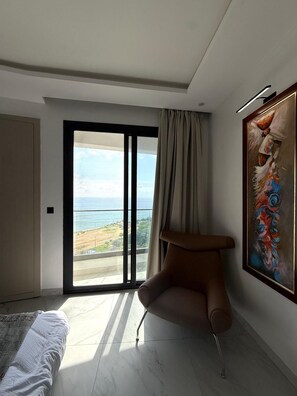 Une chambre moderne dotée d’une grande porte-fenêtre coulissante donnant sur un balcon avec vue sur la mer.