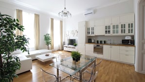 A modern living room with a glass dining table, a sofa, and a TV. - Flatiron Budapest by Hi5 (Budapest)