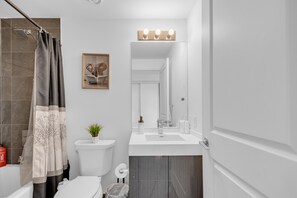 Ein modernes Badezimmer mit Dusche, Toilette, Waschbecken und Spiegel über dem Waschbecken.