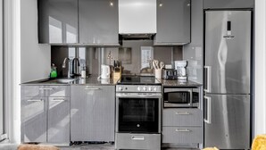 Cozinha moderna com armários cinza, uma geladeira de aço inoxidável, forno embutido, micro-ondas e fogão a gás.