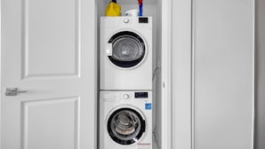 A laundry room with two stacked washing machines and a door.