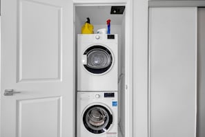 A laundry room with two stacked washing machines and a door.