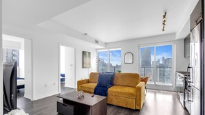 Apartamento moderno com sala de estar, cozinha e grandes janelas com vista para a cidade.