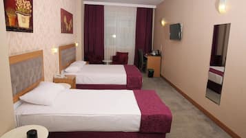 A hotel room with two beds, a desk, a chair, a small table, and a mirror.