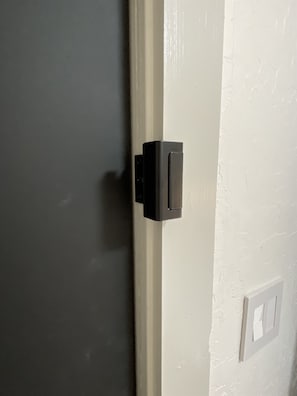 Eine Tür mit schwarzem Griff und eine weiße Wand mit sichtbarer Steckdose.