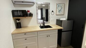 A compact kitchen with a microwave, coffee maker, and a refrigerator.