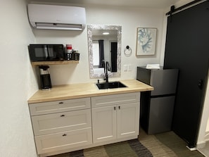 A compact kitchen with a microwave, coffee maker, and a refrigerator.