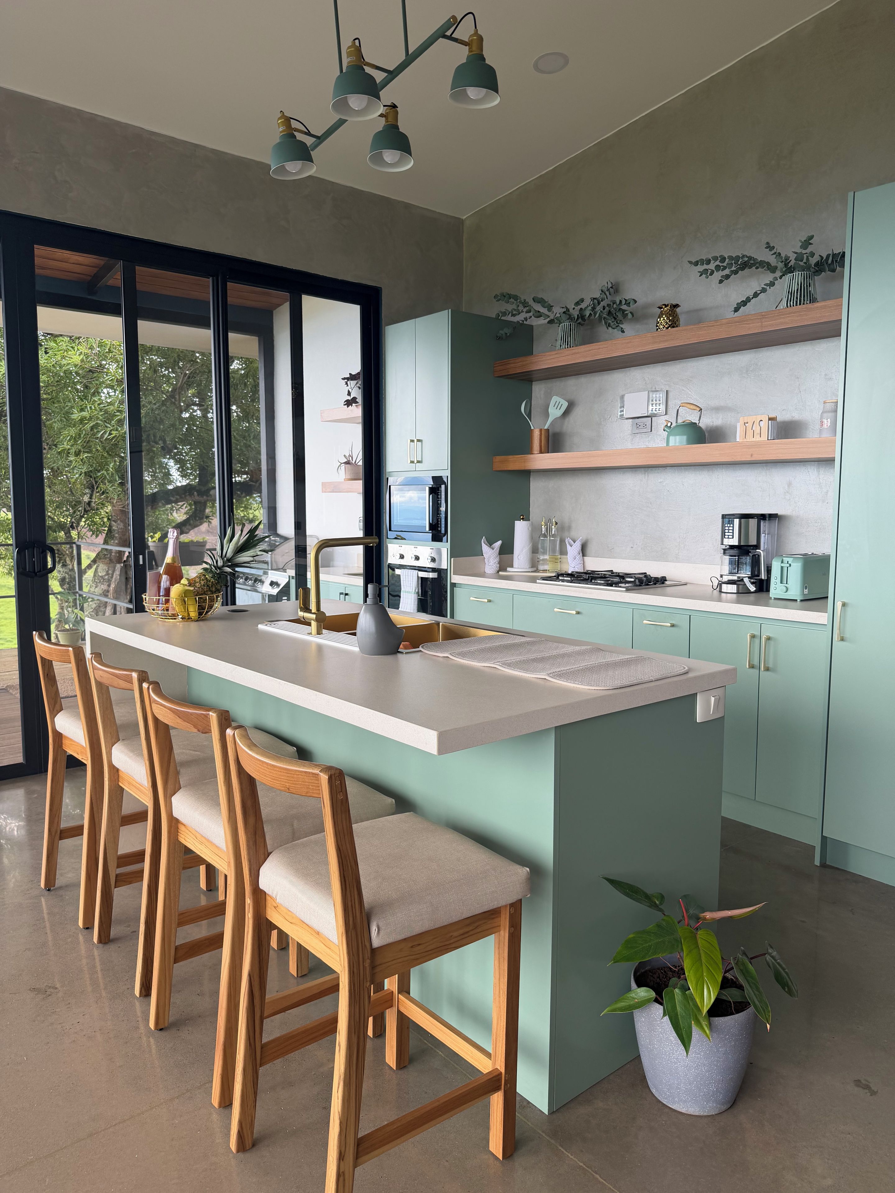 Una cocina moderna con una isla central, taburetes de bar y una planta en maceta.