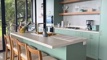 Una cocina moderna con una isla central, taburetes de bar y una planta en maceta.