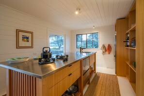 A modern kitchen with a stainless steel countertop, wooden cabinetry, and a window providing natural light.
