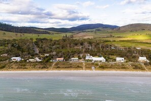 A coastal landscape with a beach, houses, and rolling hills in the background.