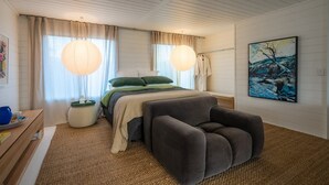 A bedroom with a bed, bedside table, lamp, and artwork.