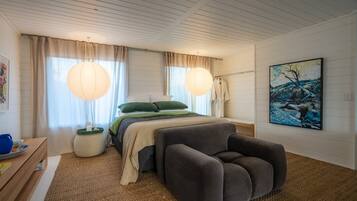 A bedroom with a bed, bedside table, lamp, and artwork.